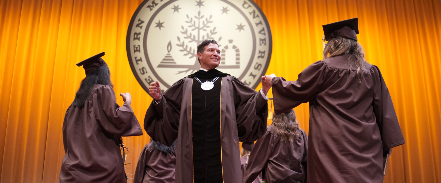President Russ Kavalhuna fist-bumps graduates on stage.