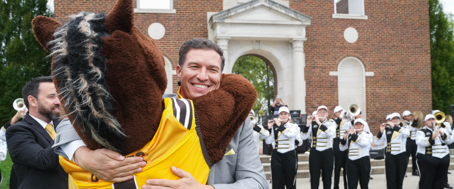 President Russ Kavalhuna hugs Buster Bronco.