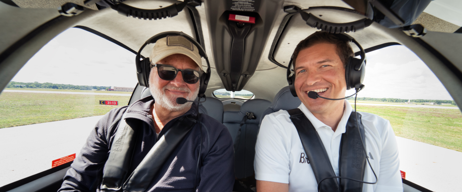 President Russ Kavalhuna and Sen. Gary Peters sit in the cockpit of an airplane.