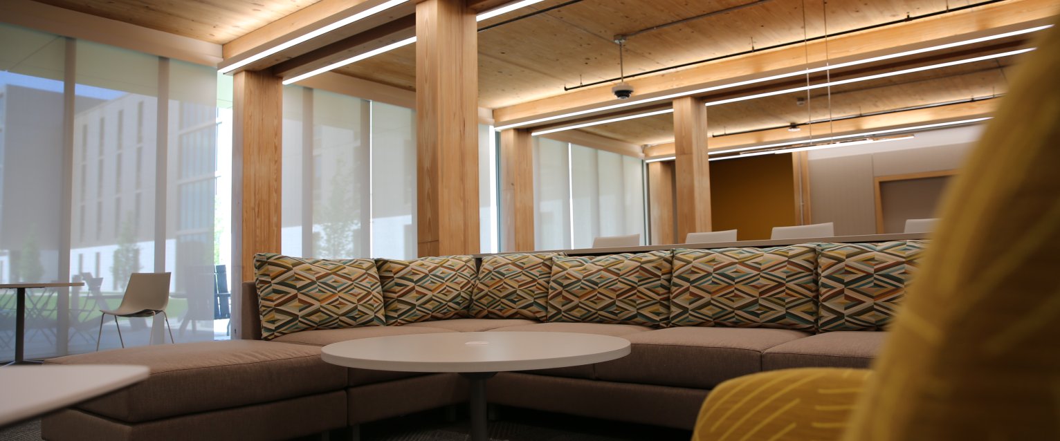 A warmly lit residence hall lounge with wood ceilings and colorful furniture.