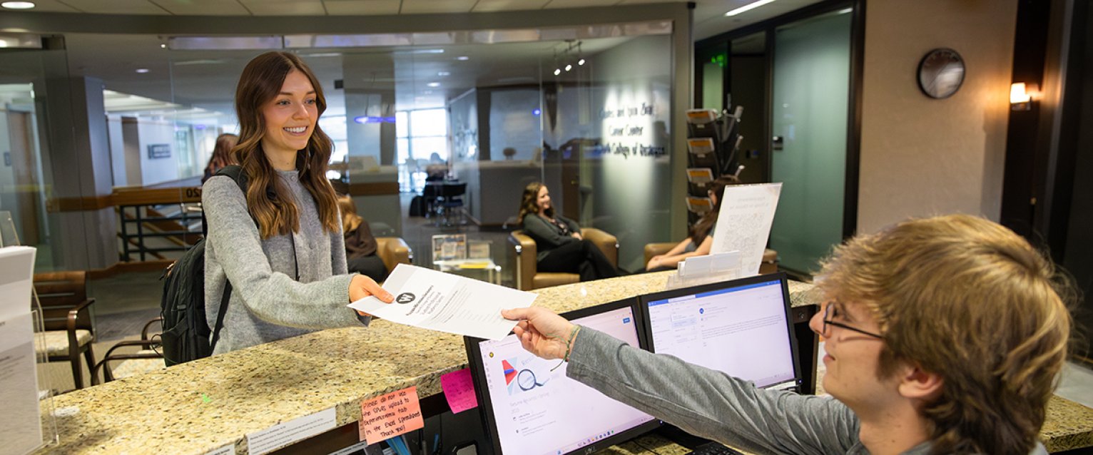 A student receiving papers from the front desk worker