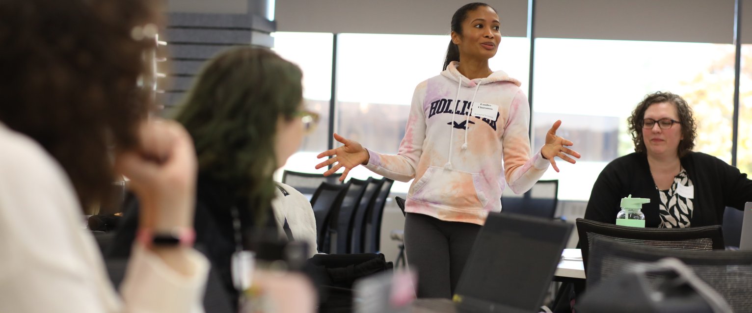 a female student in a white top speaks to a small group