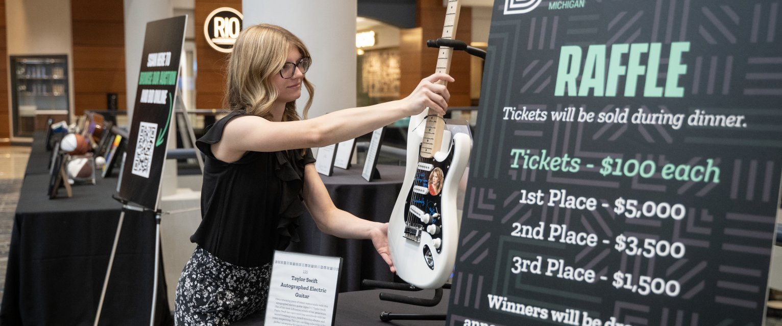 An honors student places a guitar on a stand at an event for Big Brothers, Big Sisters. 