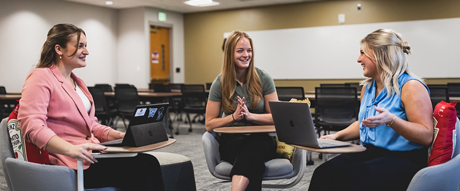 Three students sitting and talking to each other