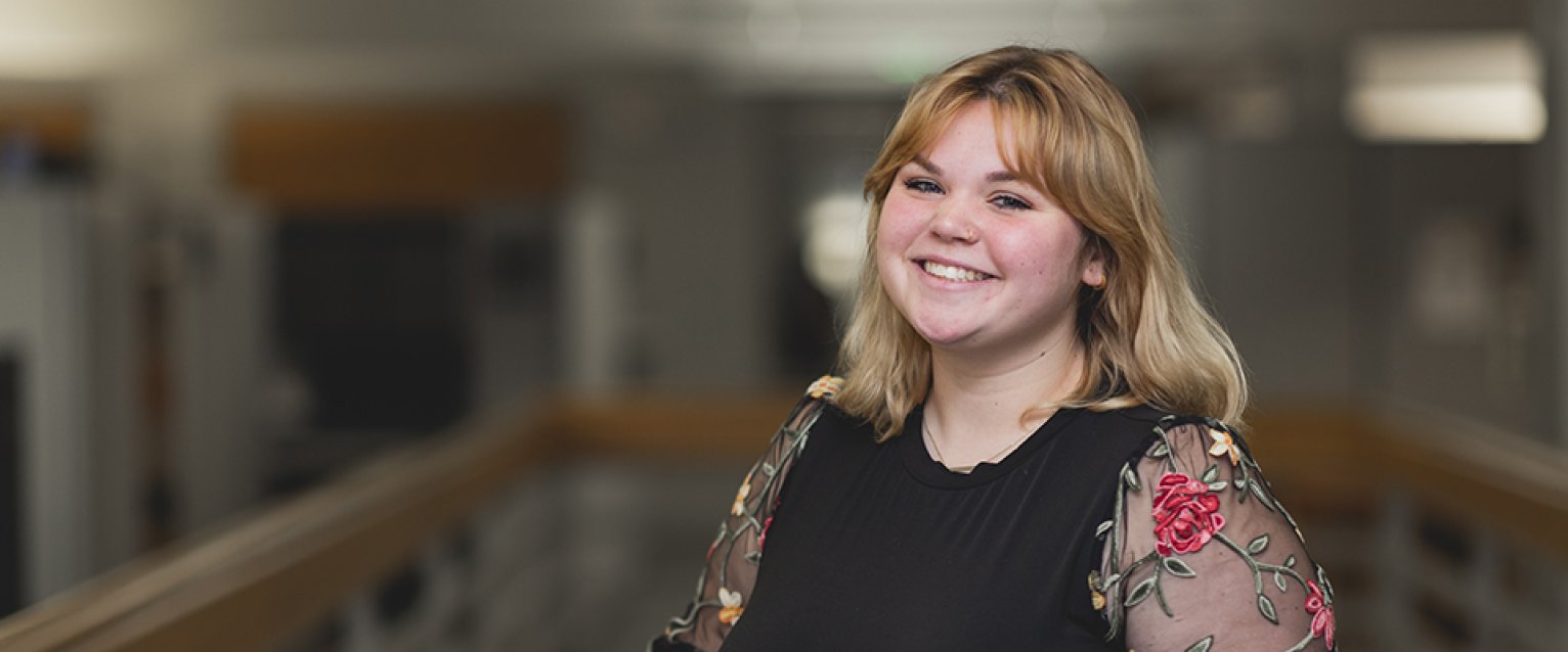 A student standing in a hallway smiling