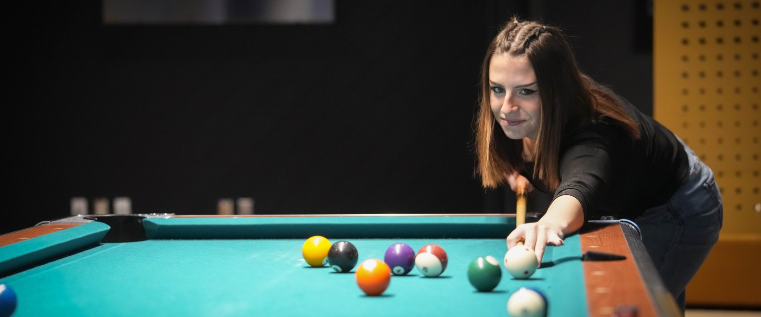 A student plays pool inside the Game On game room.