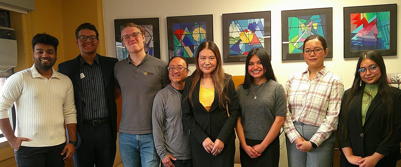 A photo of students from The Evaluation Lab posing with the Lab's director and the AEA president