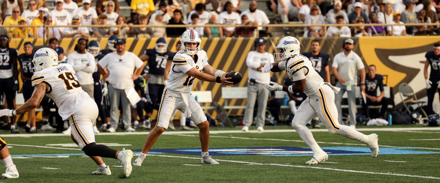 Bronco quarterback Broc Lowry prepares to hand off the football during the 2026 season home opener.