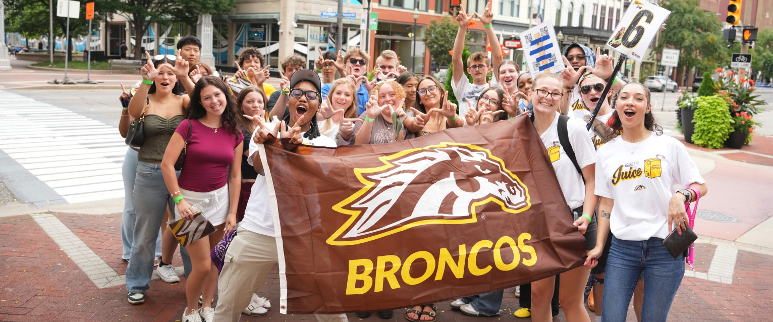 A group of Western students holds a Broncos flag in downtown Kalamazoo.