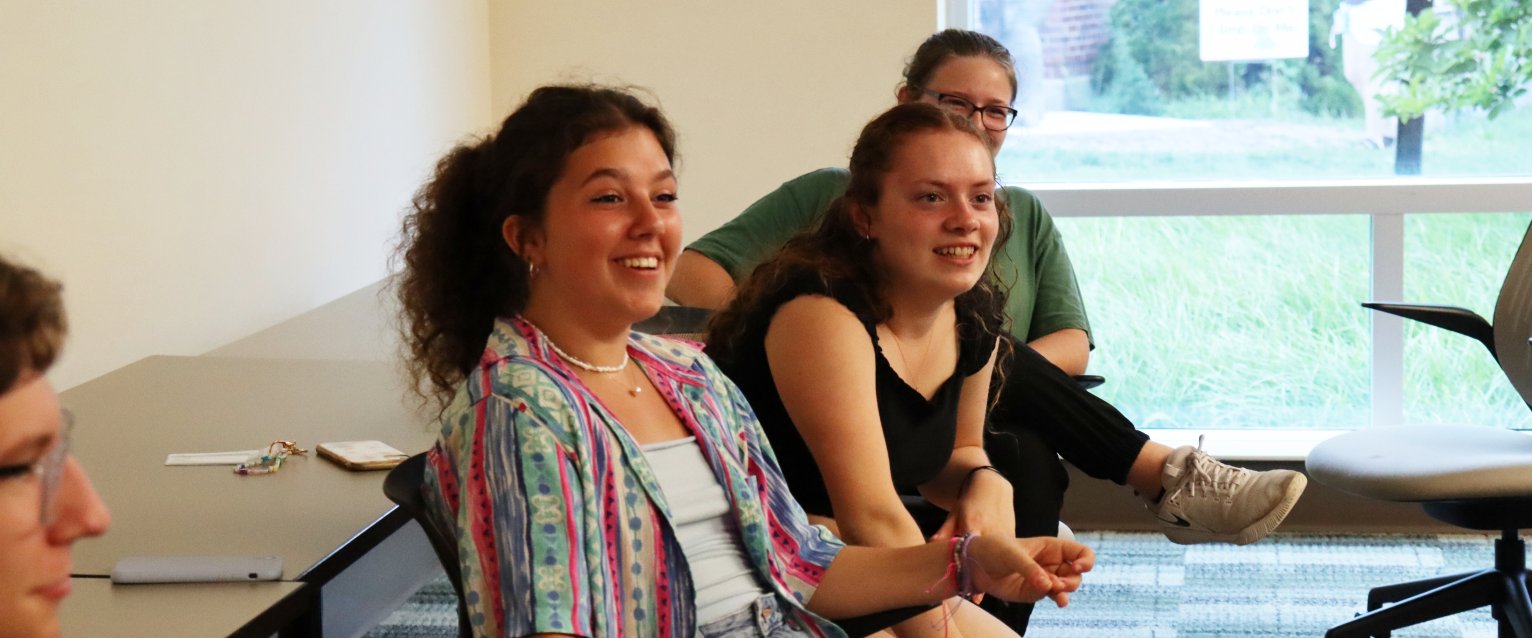 Students sit in an honors college classroom, engaged in lively conversation.