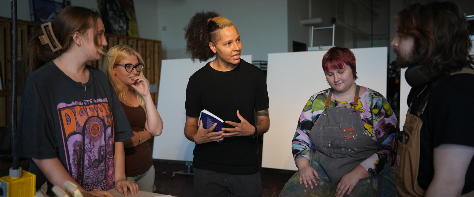 Artist Genesis Be talks to WMU students in a painting class.