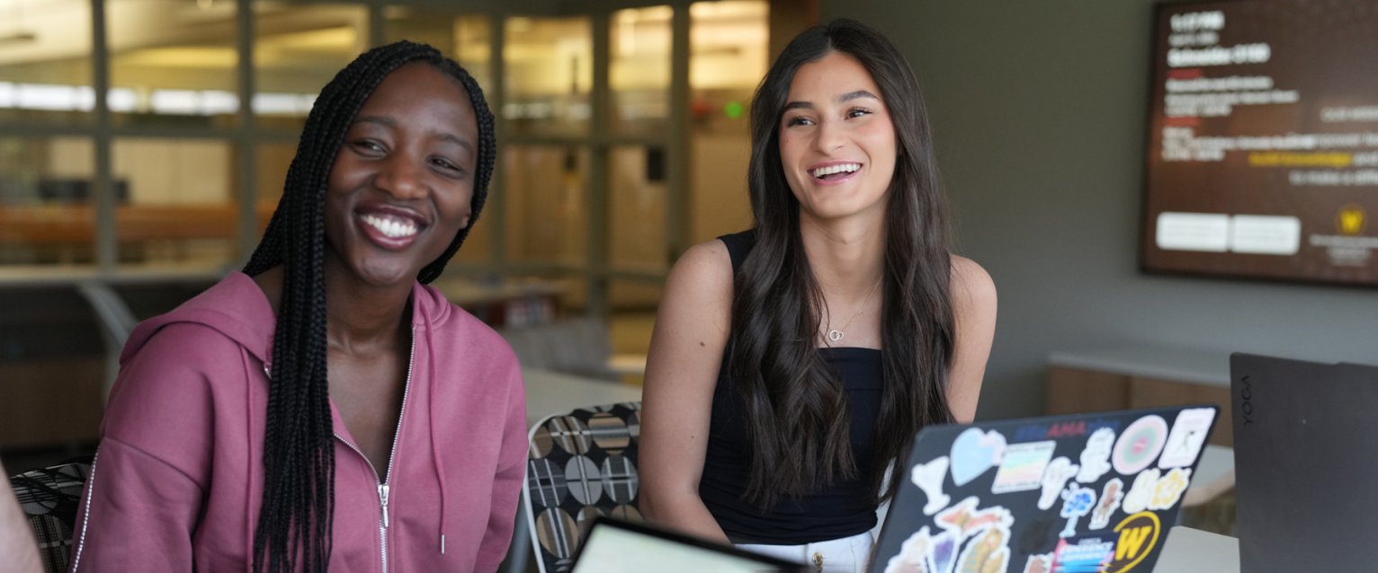Two graduate students seated with laptops