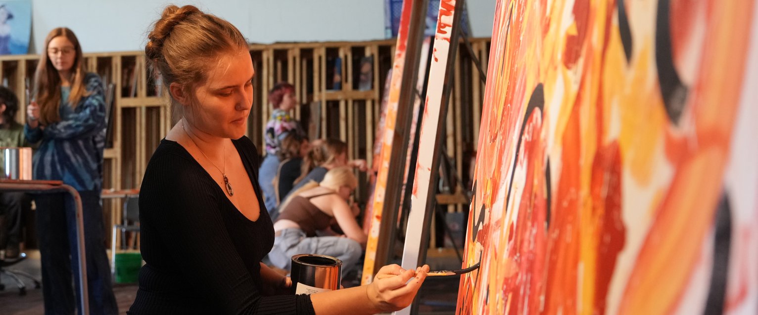 A WMU students works on a very colorful painting.