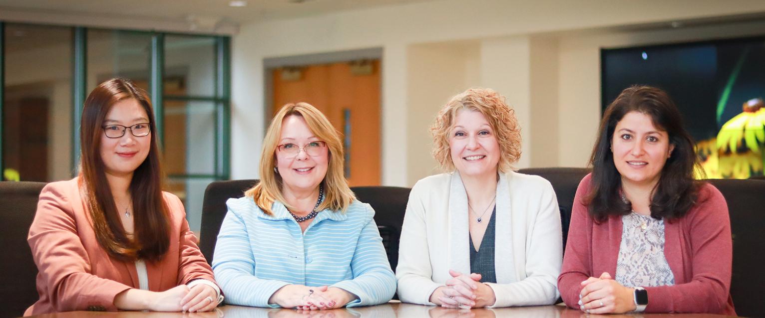 Drs. Chen Wang, Christina Stamper, Jennifer Bott and Viva Nsair are all sitting the the Dean's Conference Room.