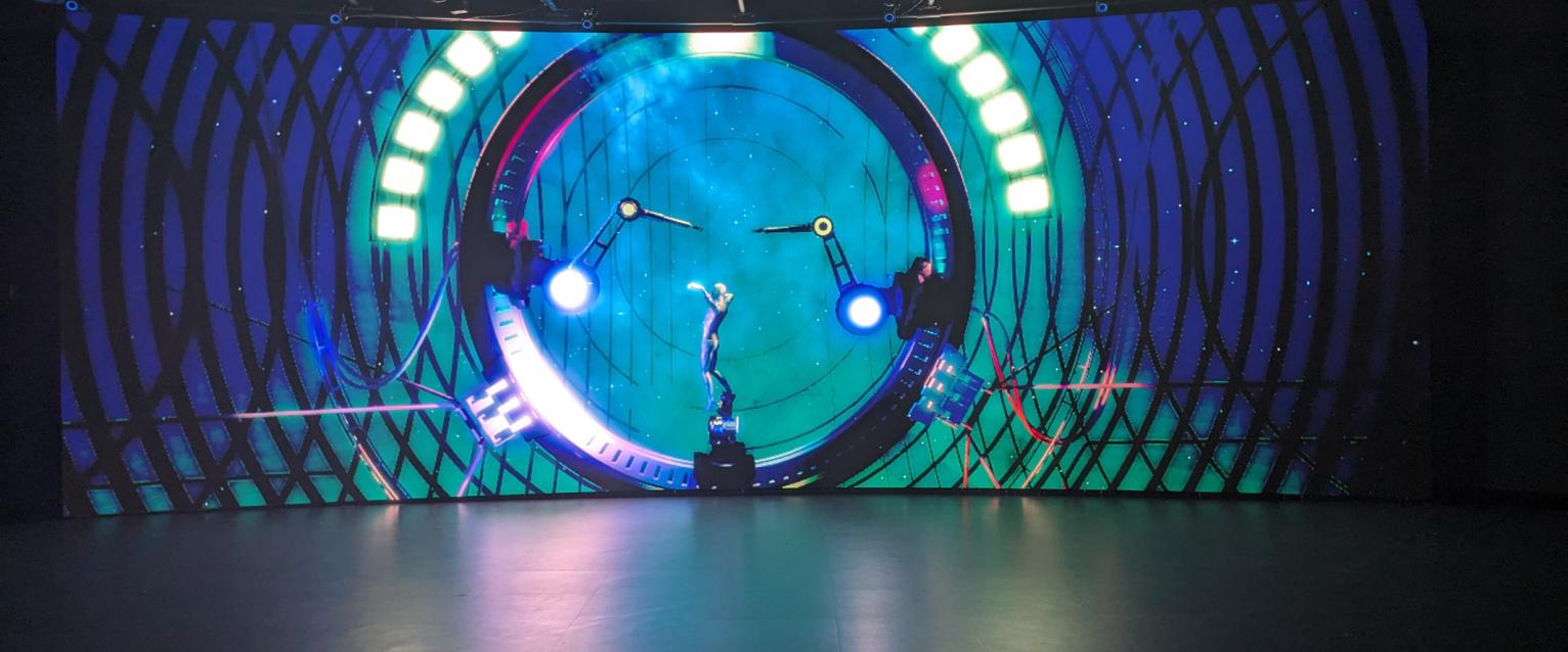 Teal 3D animation of robotic arms on LED wall.