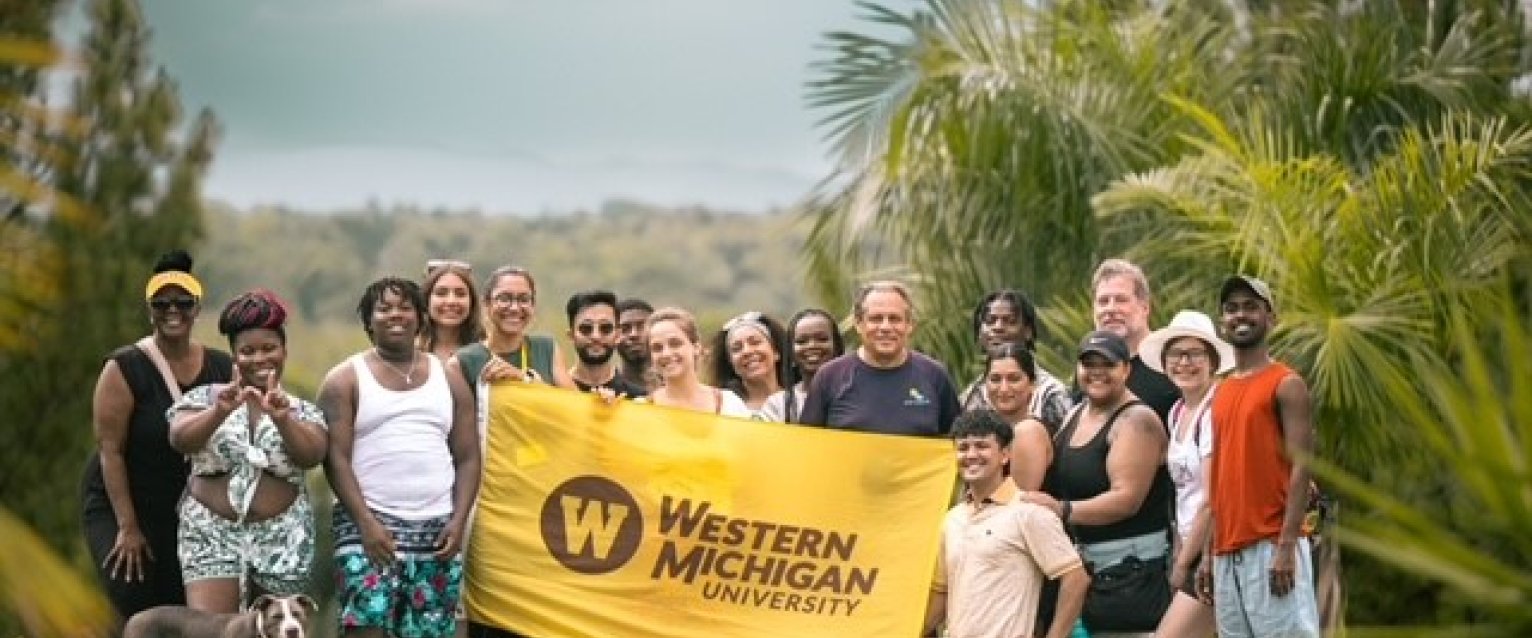 A group photo of WMU students holding a Western flag at a study abroad retreat.