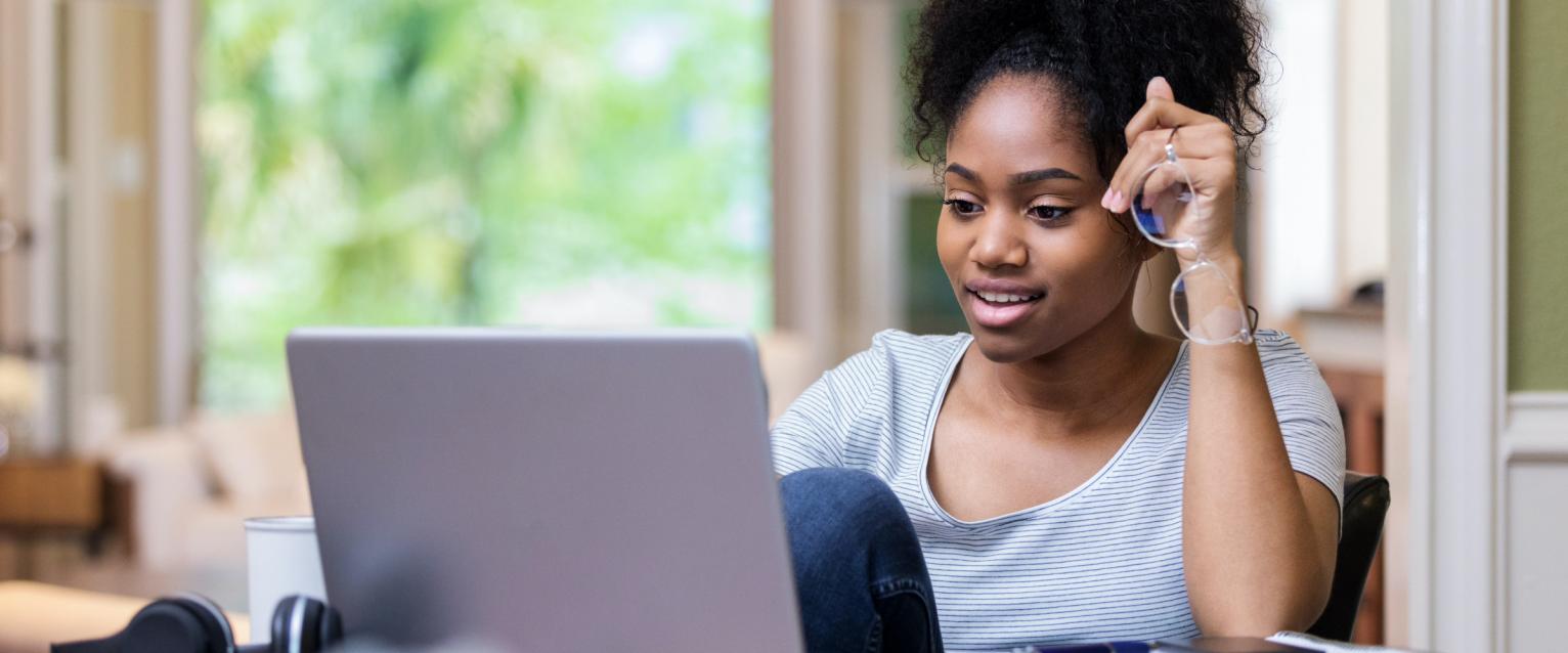 student seated at a desk using a laptop.