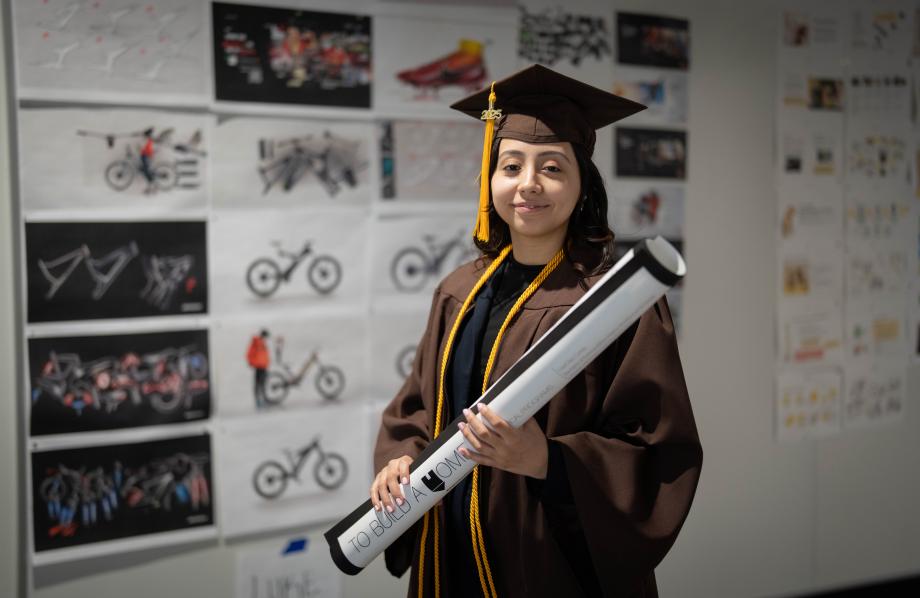 A portrait of Liset Diaz-Cortes in her cap and gown holding a blueprint.