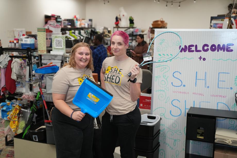 Two people hold household items in a thrift store.