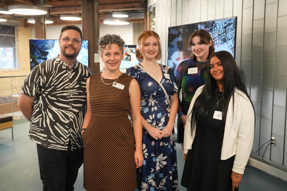 A group photo of kinetic imaging professors and students in a gallery.
