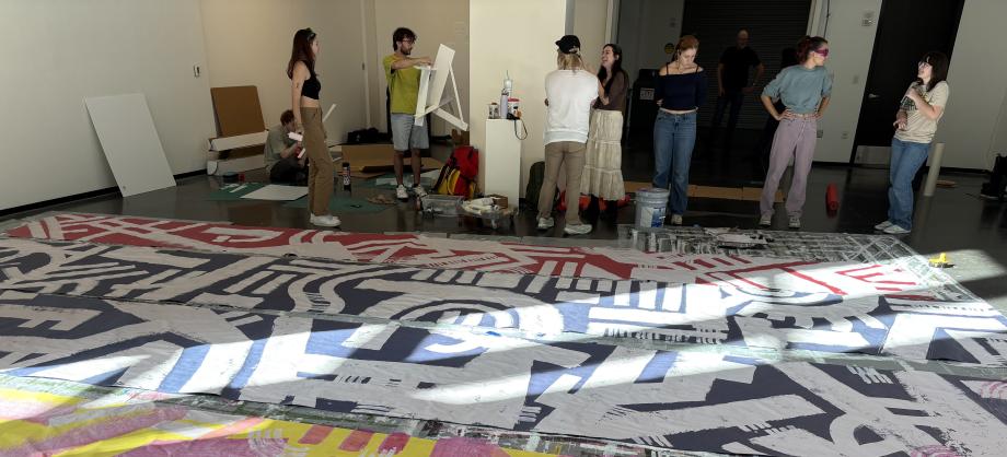 Graphic Design seniors working together in the student gallery, painting banners in bright colors.