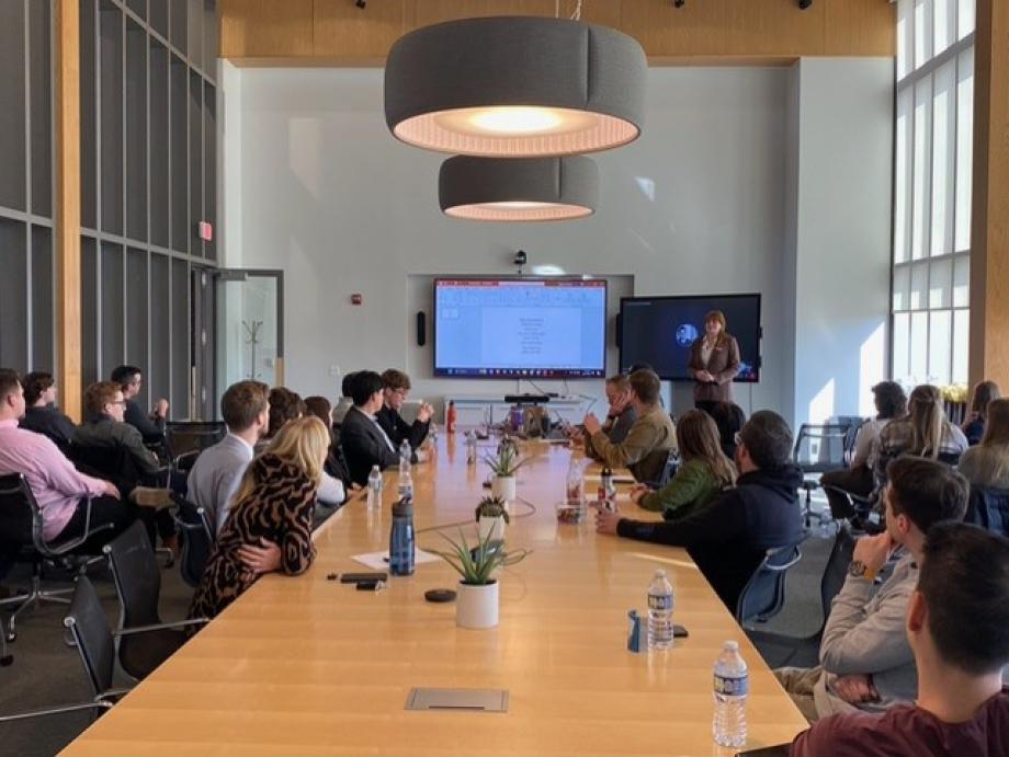 WMU students and interior design professionals sitting around a large conference table watching a presentation.