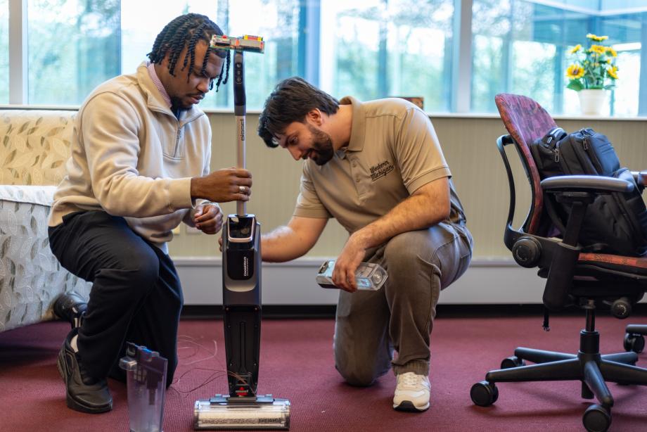 Two students with a vacuum. 