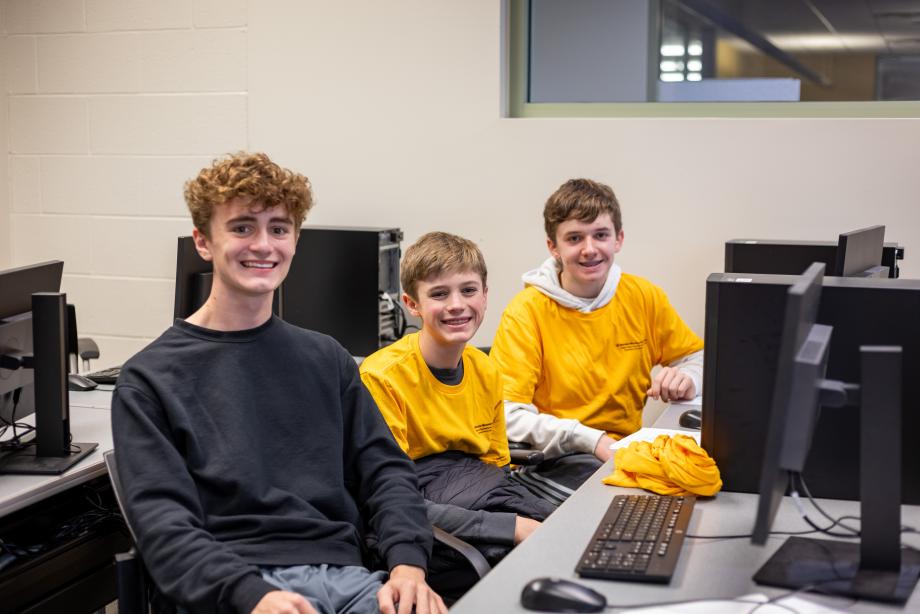 Three high school students sitting at computers. 
