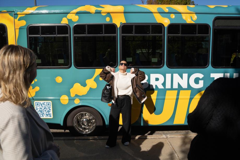 A student flexing her muscles in front of the Juice Bus.