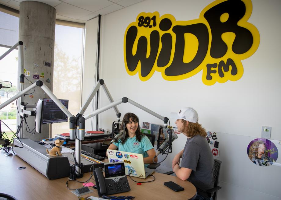 A photo of two students sitting behind microphones in the WIDR-FM recording studio.