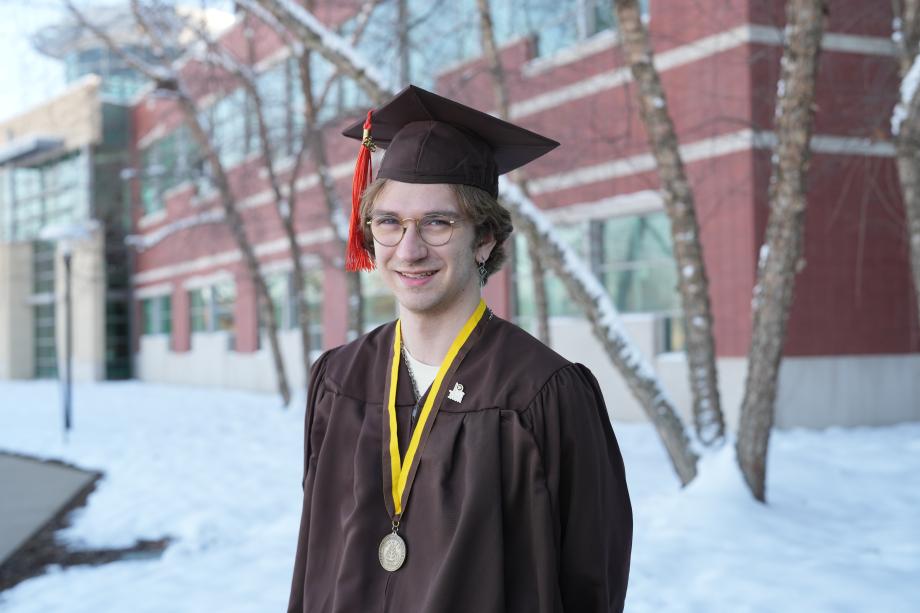 A portrait of Noah Braasch outside in his graduation regalia.