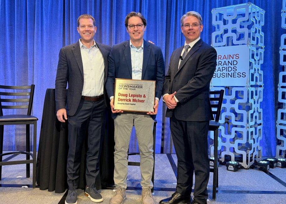 Doug Lepisto, Derrick McIver and Mickey Ciokajlo stand on stage holding an award.