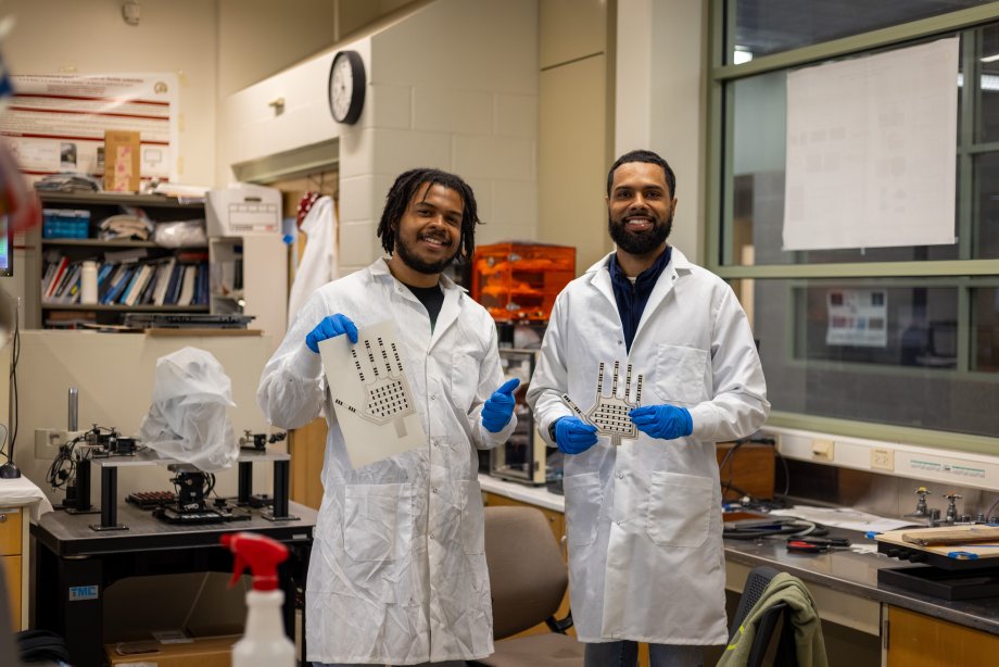 Two students holding the interior of a heated glove. 