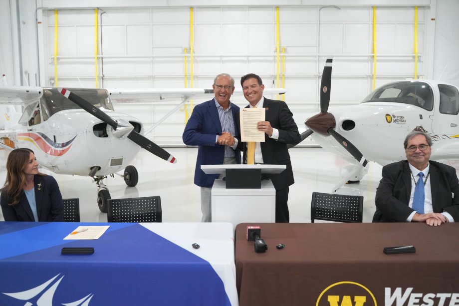 Dick DeVos and Russ Kavalhuna shake hands inside an airplane hangar.