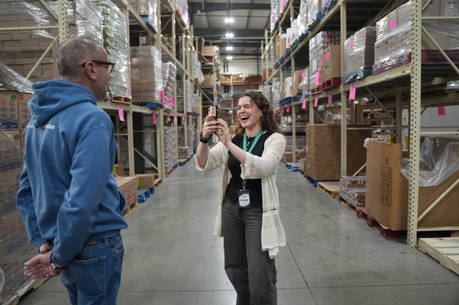 Grace Mulock takes a photo of someone in a warehouse with her cell phone.