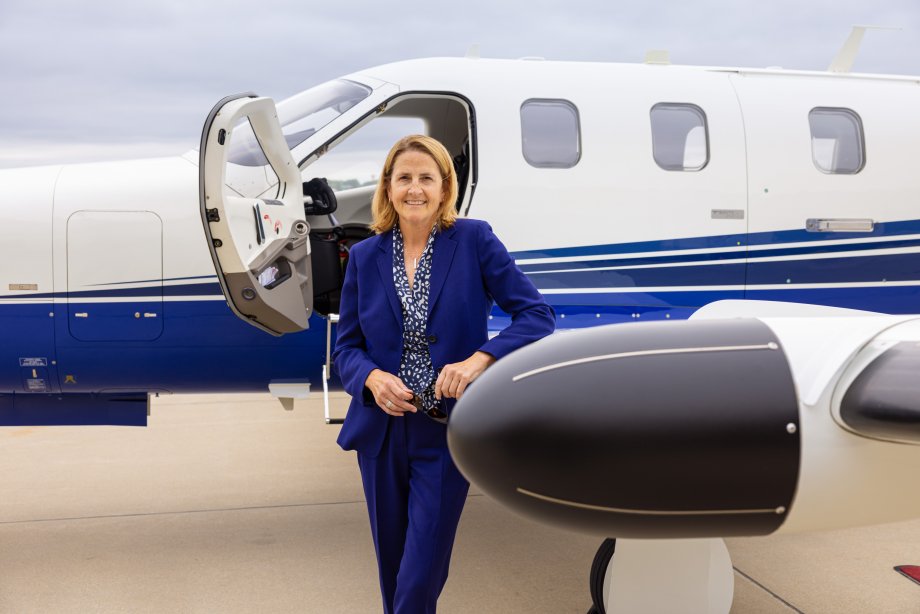 Western alumna and trustee Kelly Burris stands in front of the airplane she flies for her work as a fly-to lawyer.