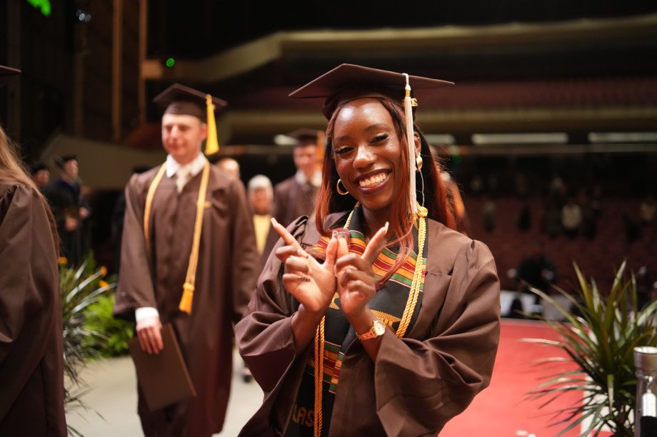 Shaniya Tate throws up the "W" sign with her hands on the commencement stage.