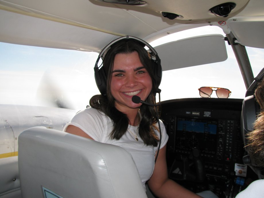 Student with headset in front seat of plane.