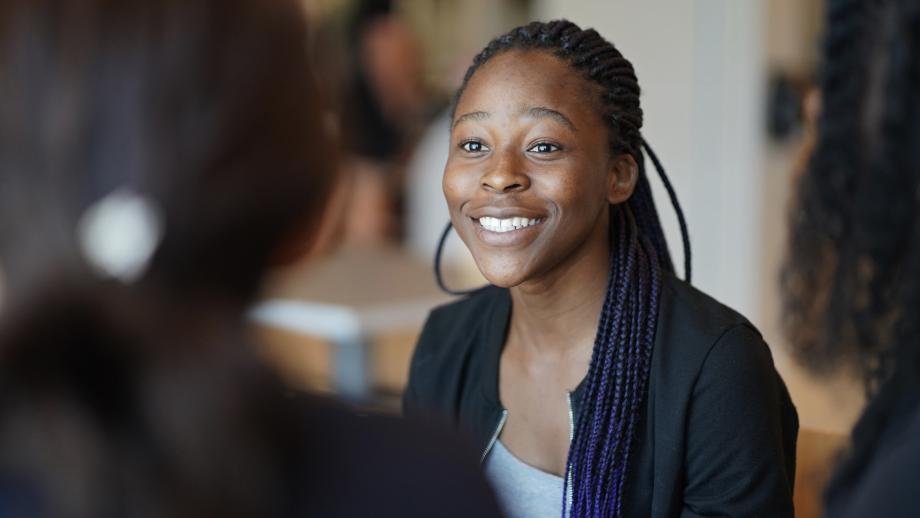 Female student smiling during discussion with classmates.