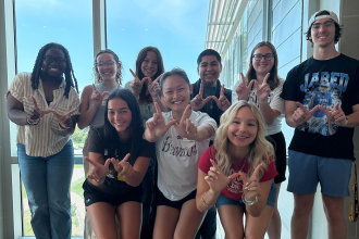 A group photo with students holding up their hands in the shape of Ws.