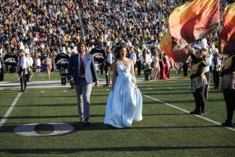 Two Homecoming Court nominees walk on the football field.