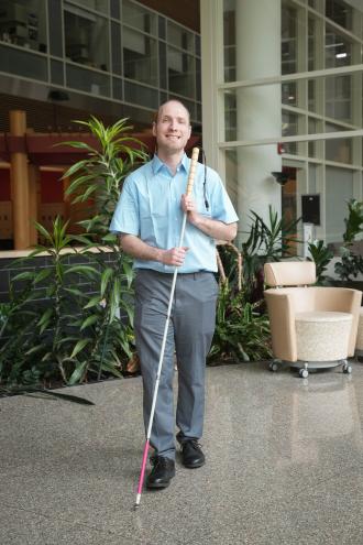 Jeffery Crouch walks through the atrium in the College of Health and Human Services with his white cane.