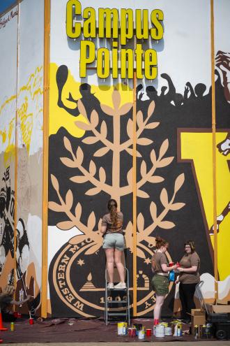 A student paints a mural.