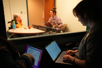 Music therapy student with a male client playing the harmonica as speech therapy students observe.