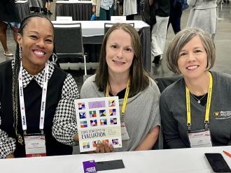 Ayesha Boyce, Kelly Robertson, and Lori Wingate sitting at an authors meet and greet event holding their book