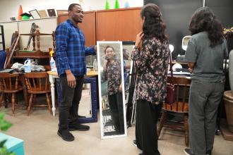 A student holds up a full-length mirror.