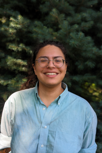 Photo of Orion Rahjes wearing a blue shirt and standing in front of a tree