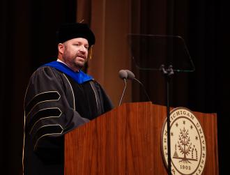 Dr. Christopher Cheatham speaking at a podium during a WMU graduation ceremony