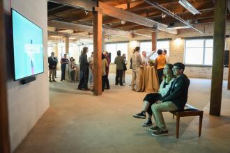 People watch a TV in an art gallery.