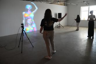 A student poses in front of a digital screen.